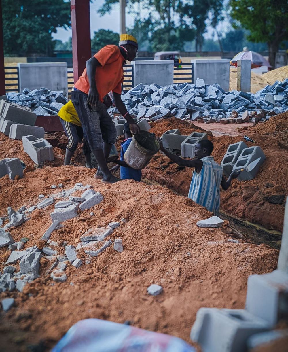 Des ouvriers se passent un seau sur un chantier