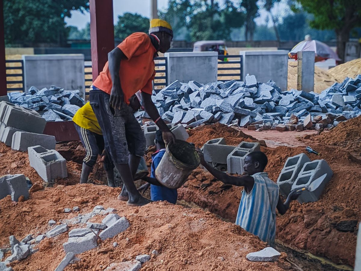 Des ouvriers se passent un seau sur un chantier